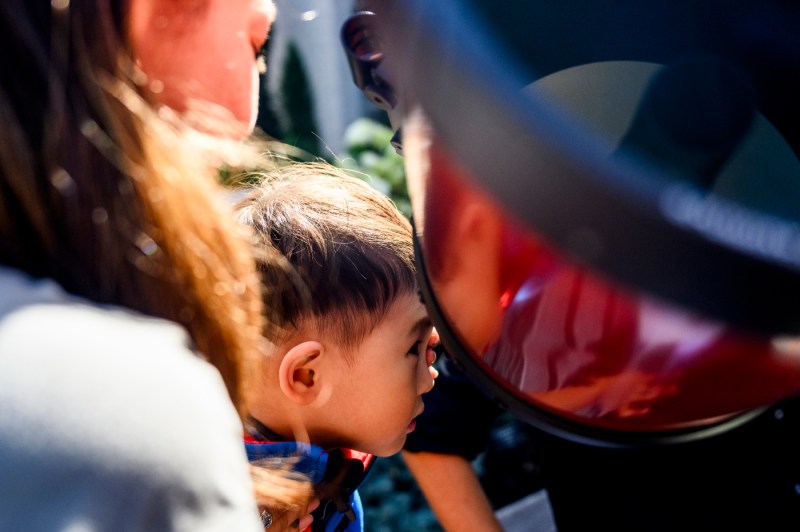 A child looks into a telescope.