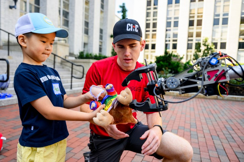 A student and a member of the Mars rover team examine a robot outside.