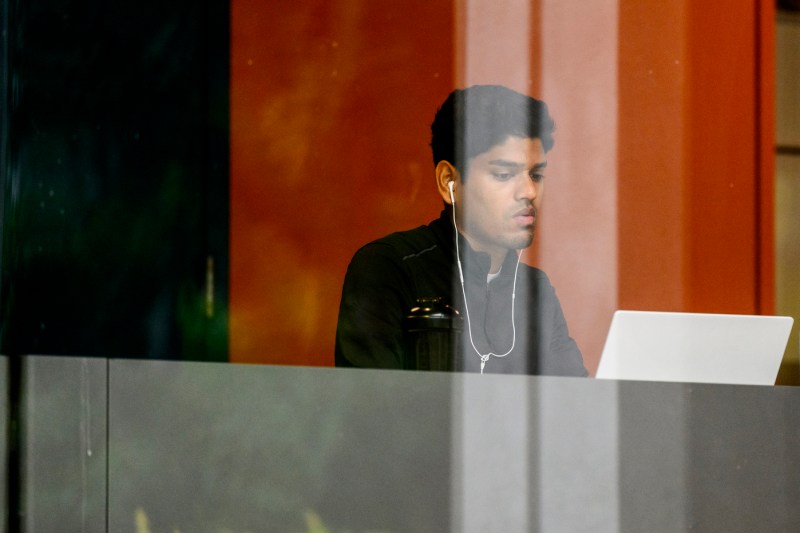 A person with wired headphones works on their laptop.