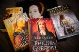 A collection of five Philippa Gregory historical fiction novels displayed on a dark surface. The books shown are &#039;The White Queen,&#039; &#039;The Red Queen,&#039; and &#039;The White Princess,&#039; all part of The Cousins&#039; War series. The book covers feature portraits of women in medieval and Tudor-era clothing and headdresses, with rich colors including gold, red, and purple. The author&#039;s name &#039;PHILIPPA GREGORY&#039; is prominently displayed on each cover.