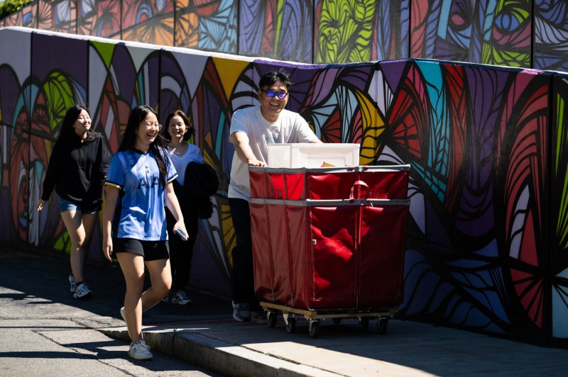 A family of four pushes a hamper full of move-in supplies.