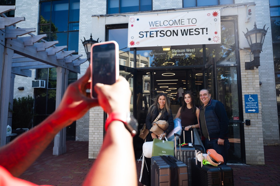 A family of four poses for a photo outside Northeastern’s Stetson West dormitory, standing beneath a large “Welcome to Stetson West!” banner.