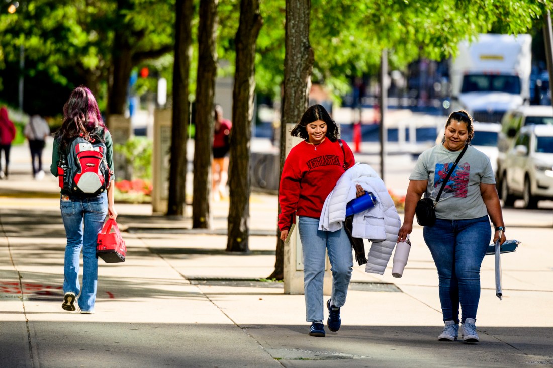 Several people carrying items down a sidewalk.