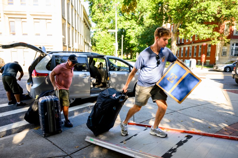 A family unloads a van of move-in supplies.