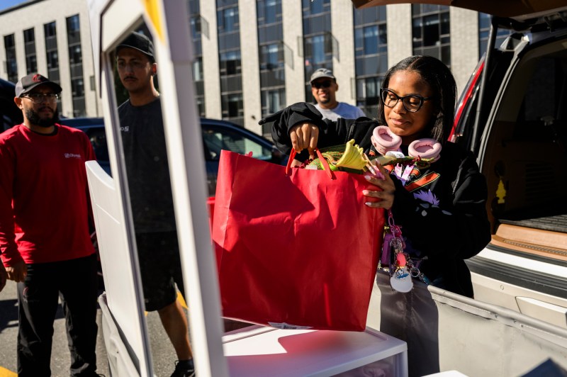 People unload a car of move-in supplies, including a mirror.