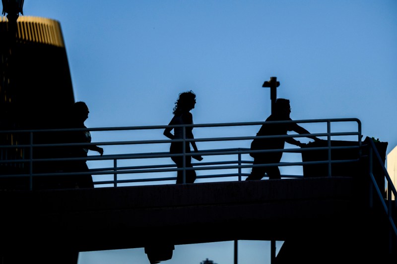 People walk across a bridge pushing a hamper of move-in supplies.