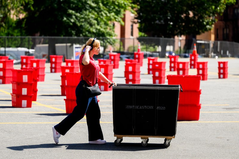 A person pushes a hamper full of move-in supplies.