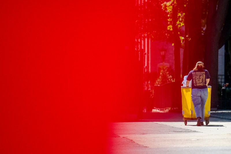 A person pushes a hamper full of move-in supplies.