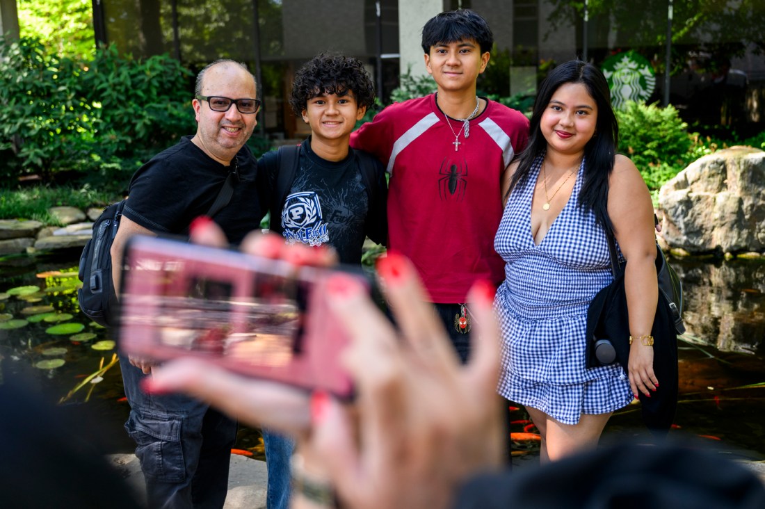 A family of four -- an older man, two sons, and a mother -- pose for a photo on the Boston campus.