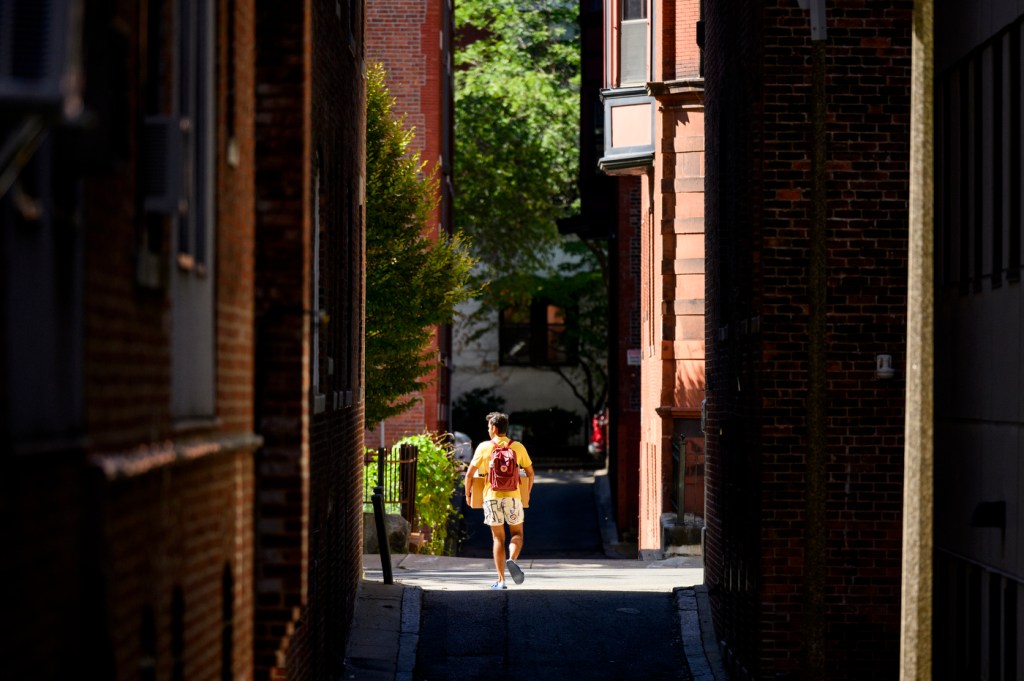 A person crossing the street between two buildings.