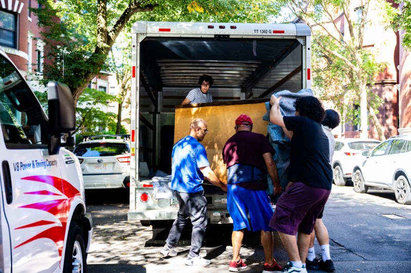 People unpack a moving truck full of furniture.