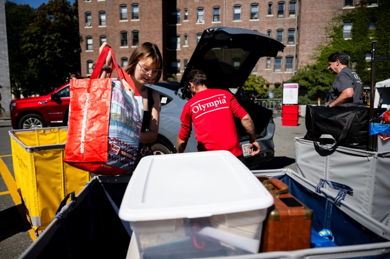 People unload cars while packing hampers full of move-in supplies.