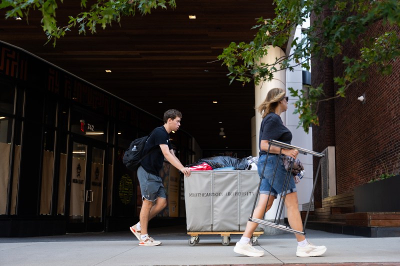 A student pushes a hamper full of move-in supplies.