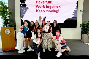 A group of Northeastern staffers who participated in the event shown posing together on a small stage.