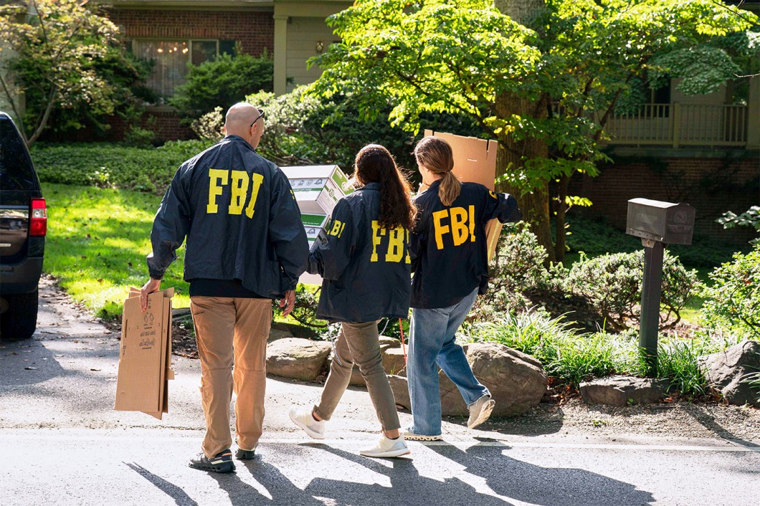 FBI agents shown carrying boxes in front of a residence in broad daylight.