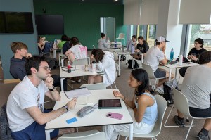 A wide view of a room full of students working and collaborating.