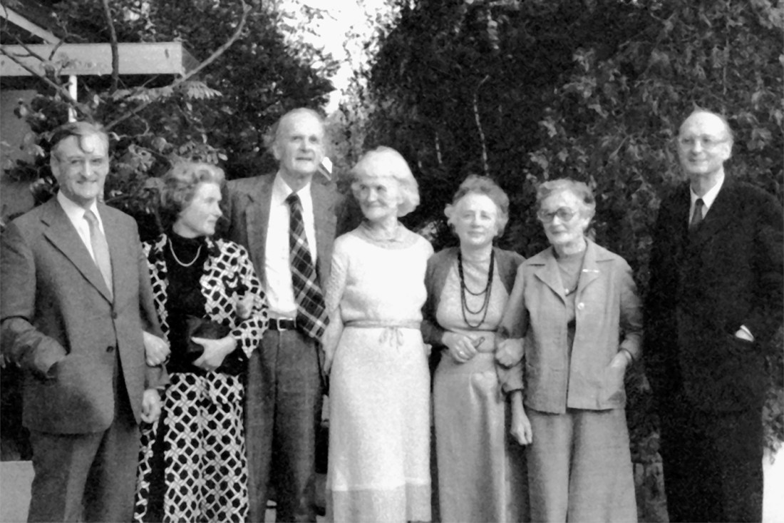 A black-and-white group photo taken outside. Everyone is wearing a dress or a suit and tie.