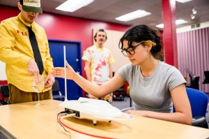 A student playing a theremin while others watch.