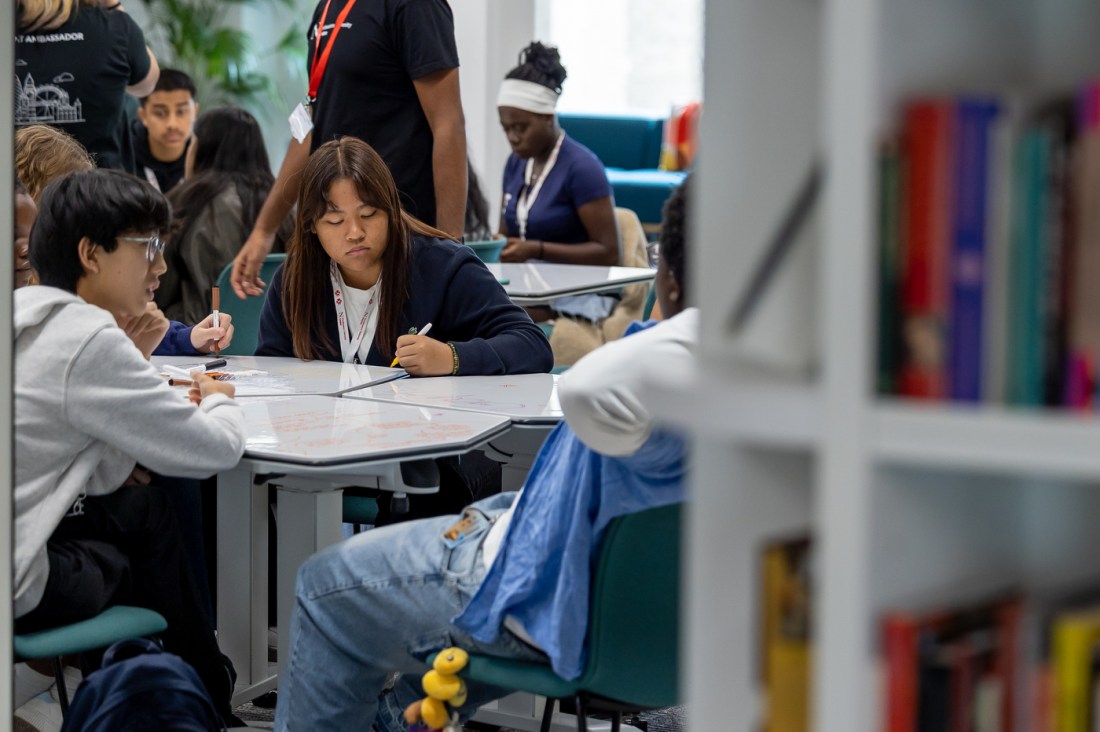Students talking together and writing on a tabletop whiteboard.