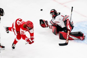 A northeastern goalie moves to block the puck as another player falls.
