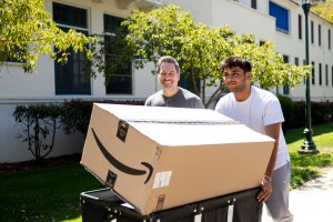 A Northeastern student and another man shown smiling and carrying an Amazon package during Welcome Week.