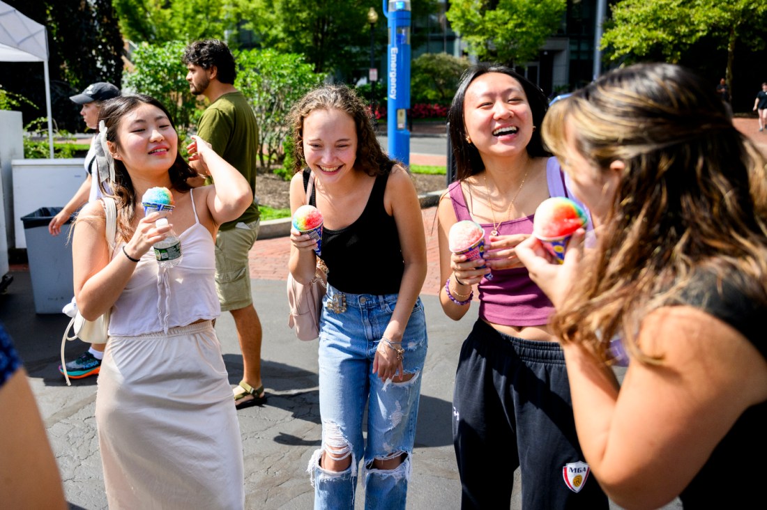 A group of students standing together and laughing while eating sno cones.