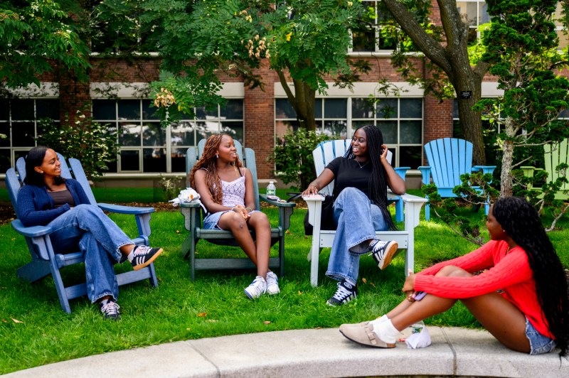 Students sit in Adirondack chairs on the Boston campus. 