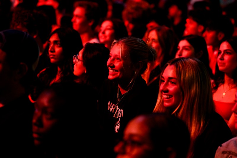 Students in the crowd at convocation smile.