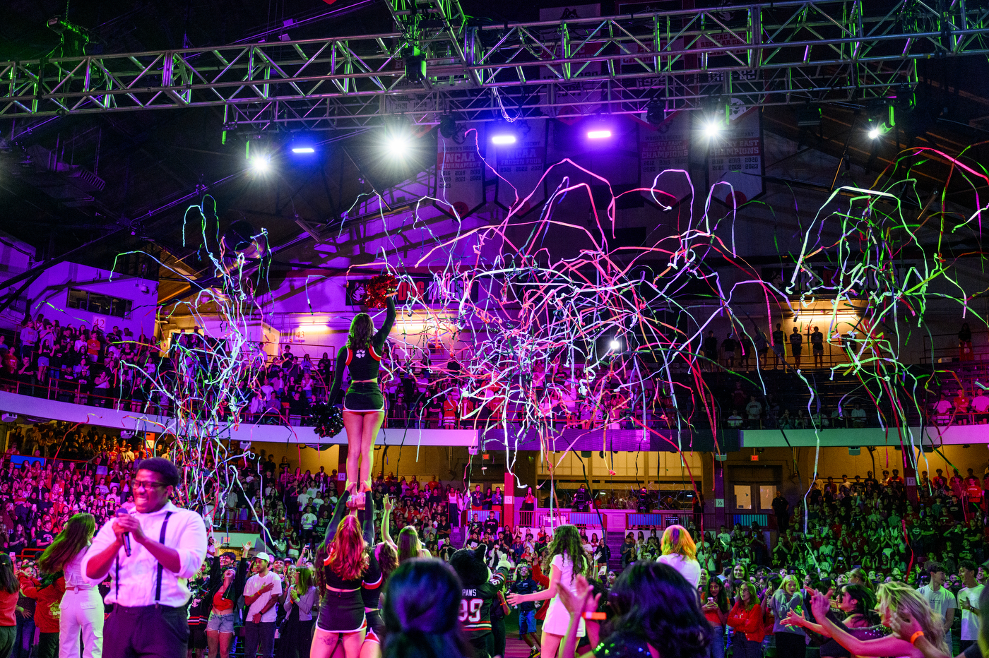 Confetti flows into the air as colorful lights play in front of a packed arena overhead.
