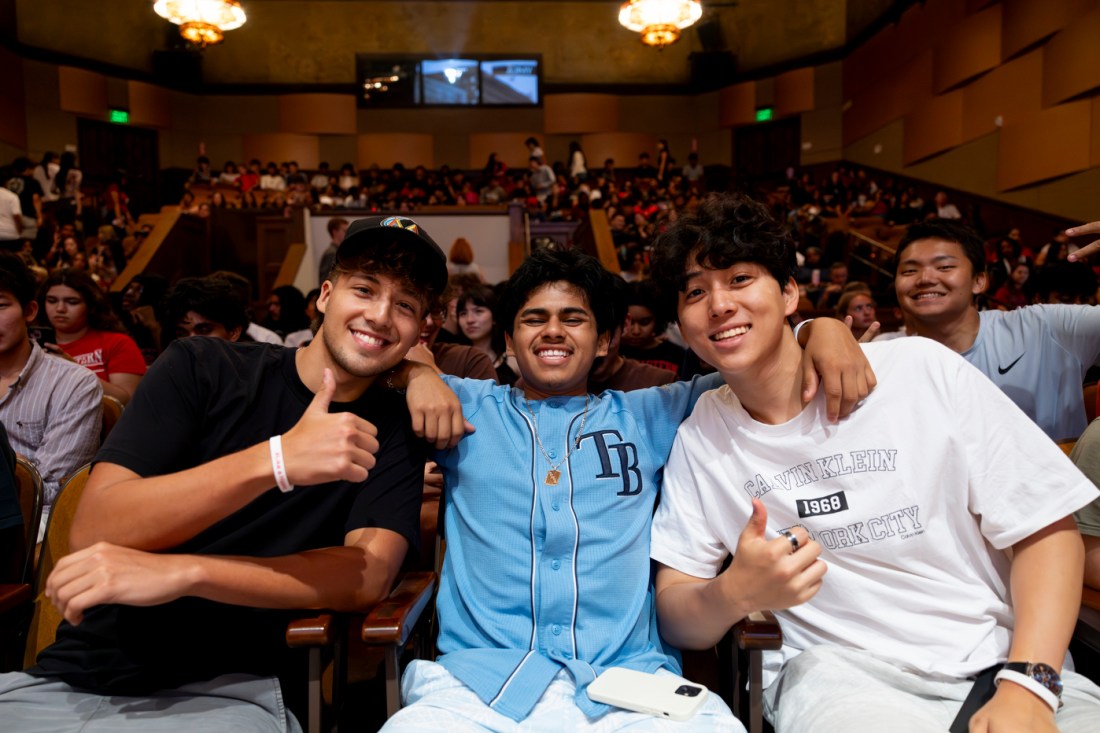 A group of students smile and give thumbs up while seated inside Littlefield Concert Hall at the Oakland campus welcome event.