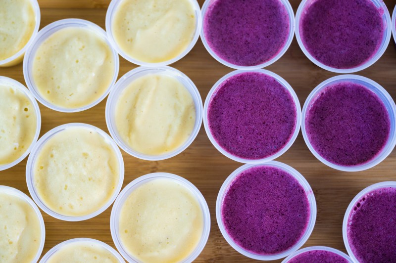 Several items from the juice bar in cups containing purple and white liquid.