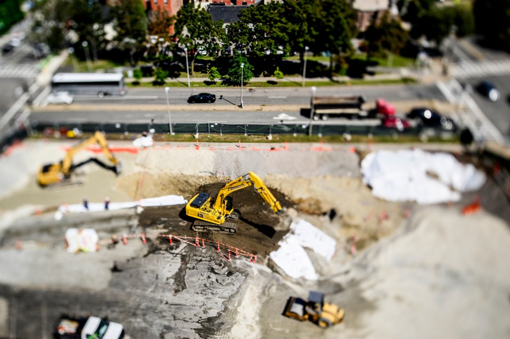 A photo of excavator digging in the dirt taken through a tilt-shift lens.