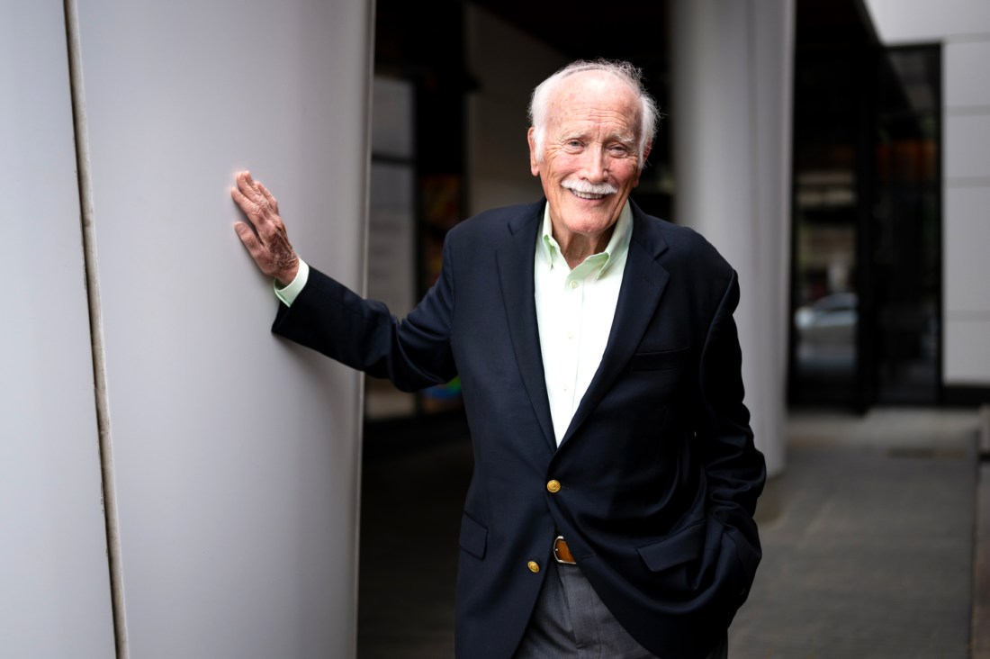 Bill Fowler, an emeritus professor of history, shown in a blue blazer smiling against a white wall.