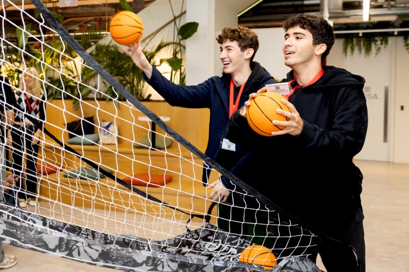 Two light-skinned male students play basketball.