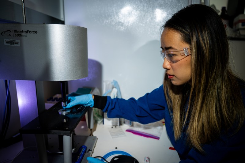 A female student wearing goggles operates lab equipment.