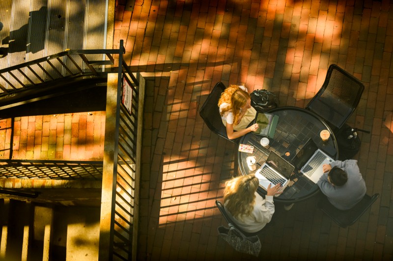 An overhead photograph of people sitting at a round table outside.