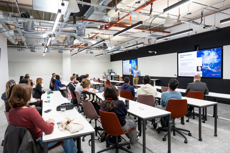 People fill a room while a person presents.