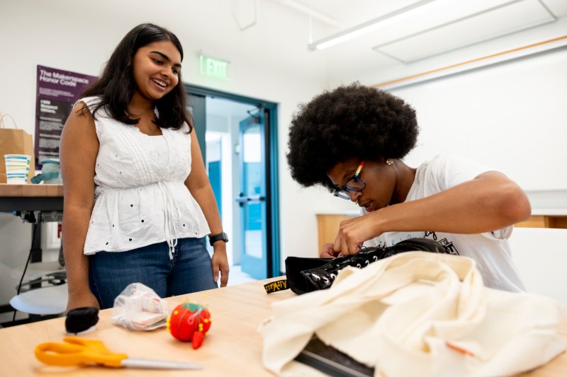 A person helps another person mend a boot.