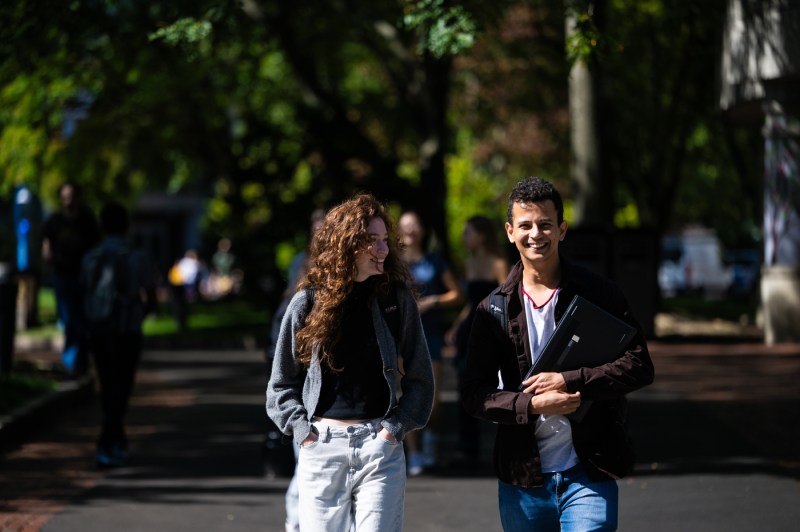 Two people walk through the Boston campus while smiling. 