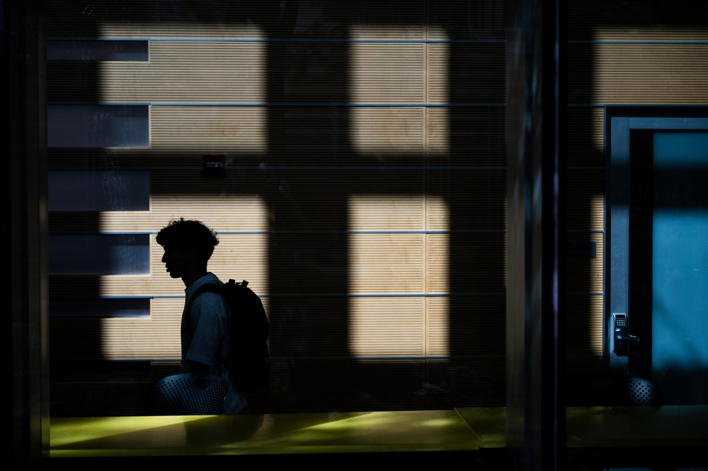 A student walks past windows.