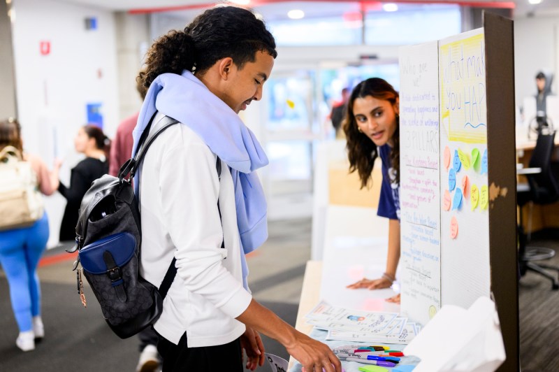 A student examines the materials laid out on the table beside posters detailing club activities.