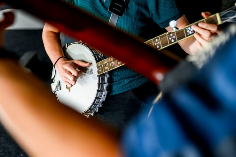 A close-up photo of a person's hands playing the banjo.