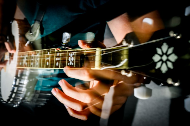A close-up photo of a person's hands playing the banjo.
