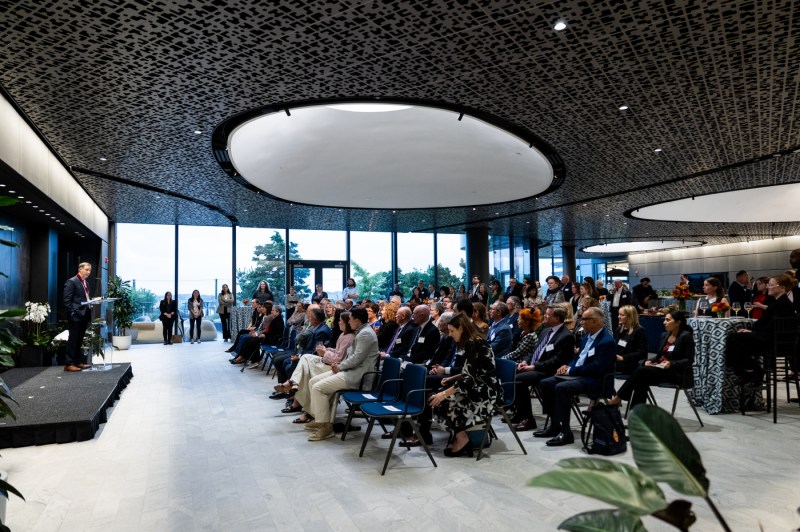 Charles Hillman speaks at a podium, as ceremony attendees sit in rows.