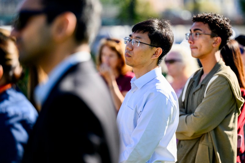 Shang Liu stands in a crowd outside at a press conference.
