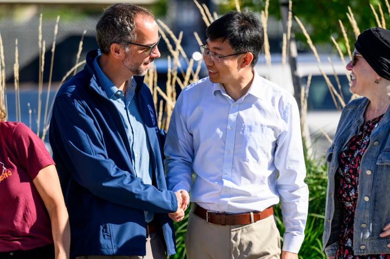 Shang Liu shakes hands with another person at a press conference.