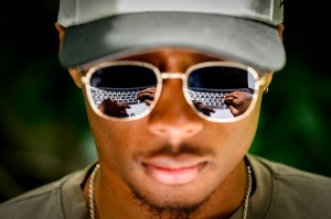 Close-up of Stephen Jacques, a Northeastern finance student, with a laptop keyboard reflected in his sunglasses as he works outside Snell Engineering Center.