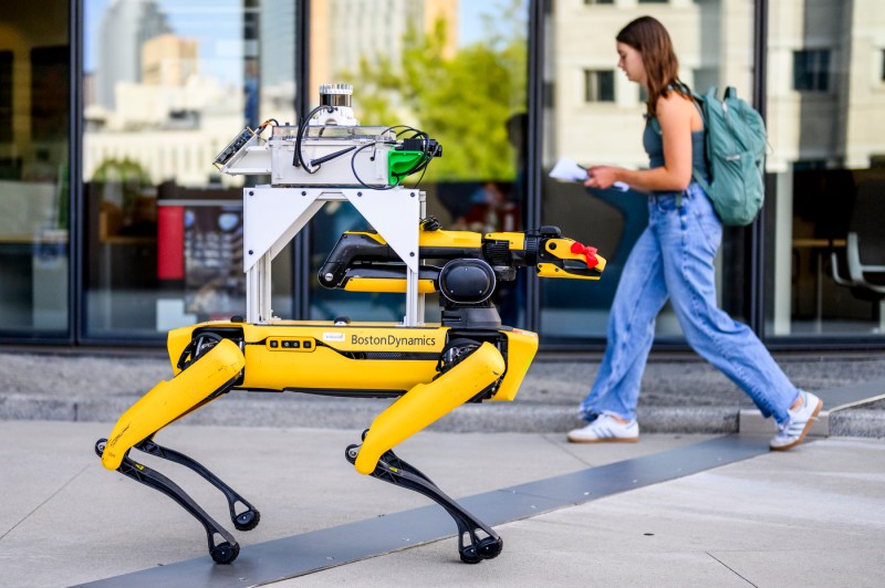 A robot walks near a student on the Boston campus.