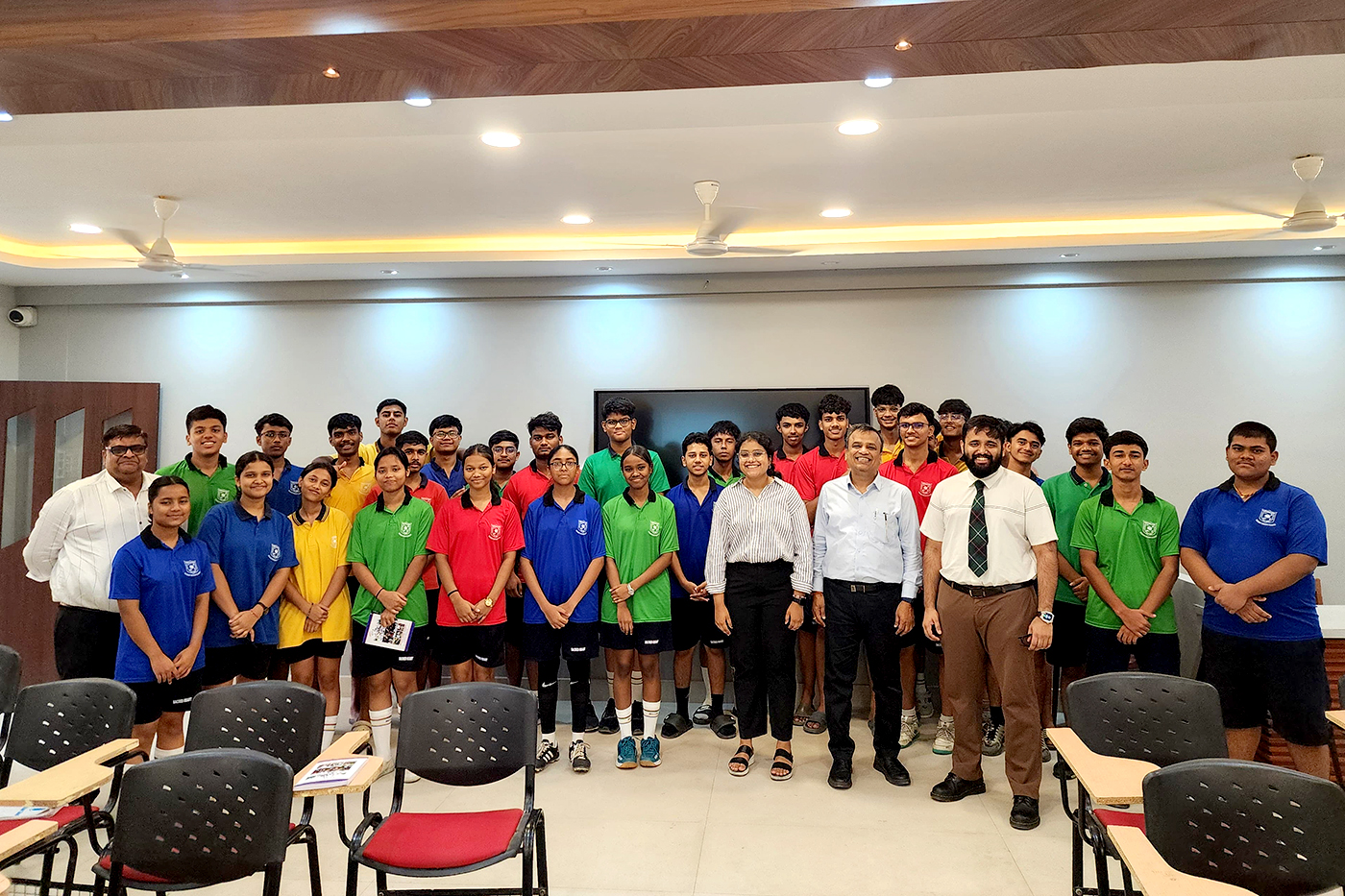 A group of Indian students and educators shown smiling in colorful shirts.
