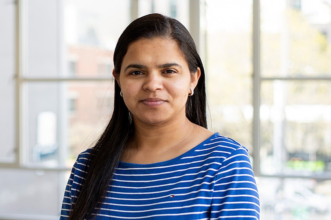Portrait of Divya Chaudhary wearing a blue shirt with white strips.